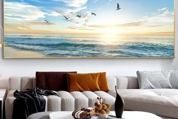 a low white sofa and coffee table sit beneath an extremely large and bright framed picture of the ocean with seagulls flying above it
