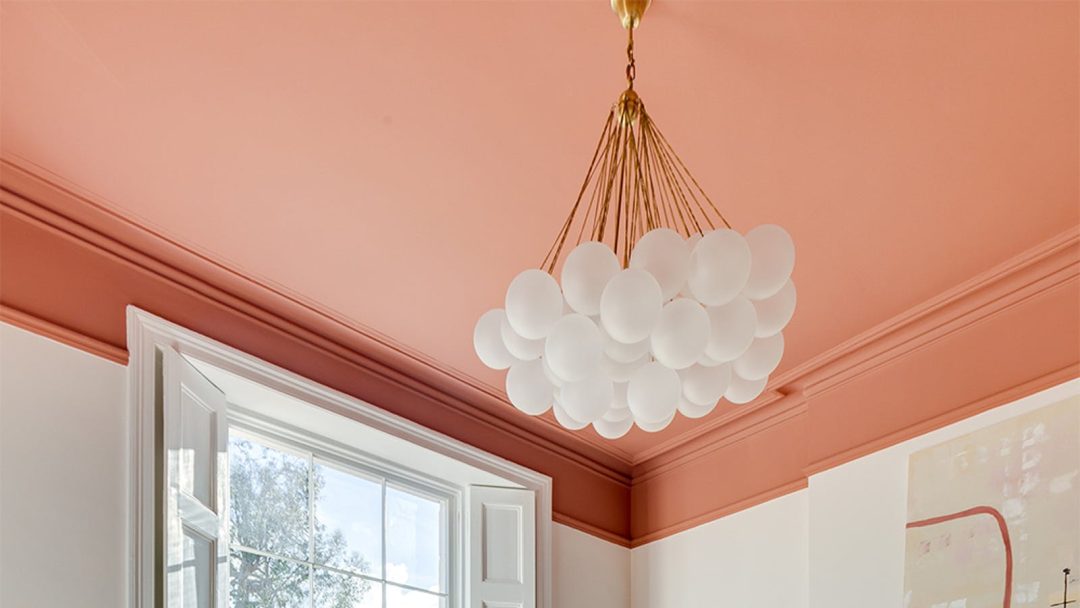 White ceiling lights hanging down from a ceiling painted in a bold shade of pink
