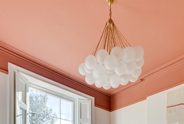 White ceiling lights hanging down from a ceiling painted in a bold shade of pink